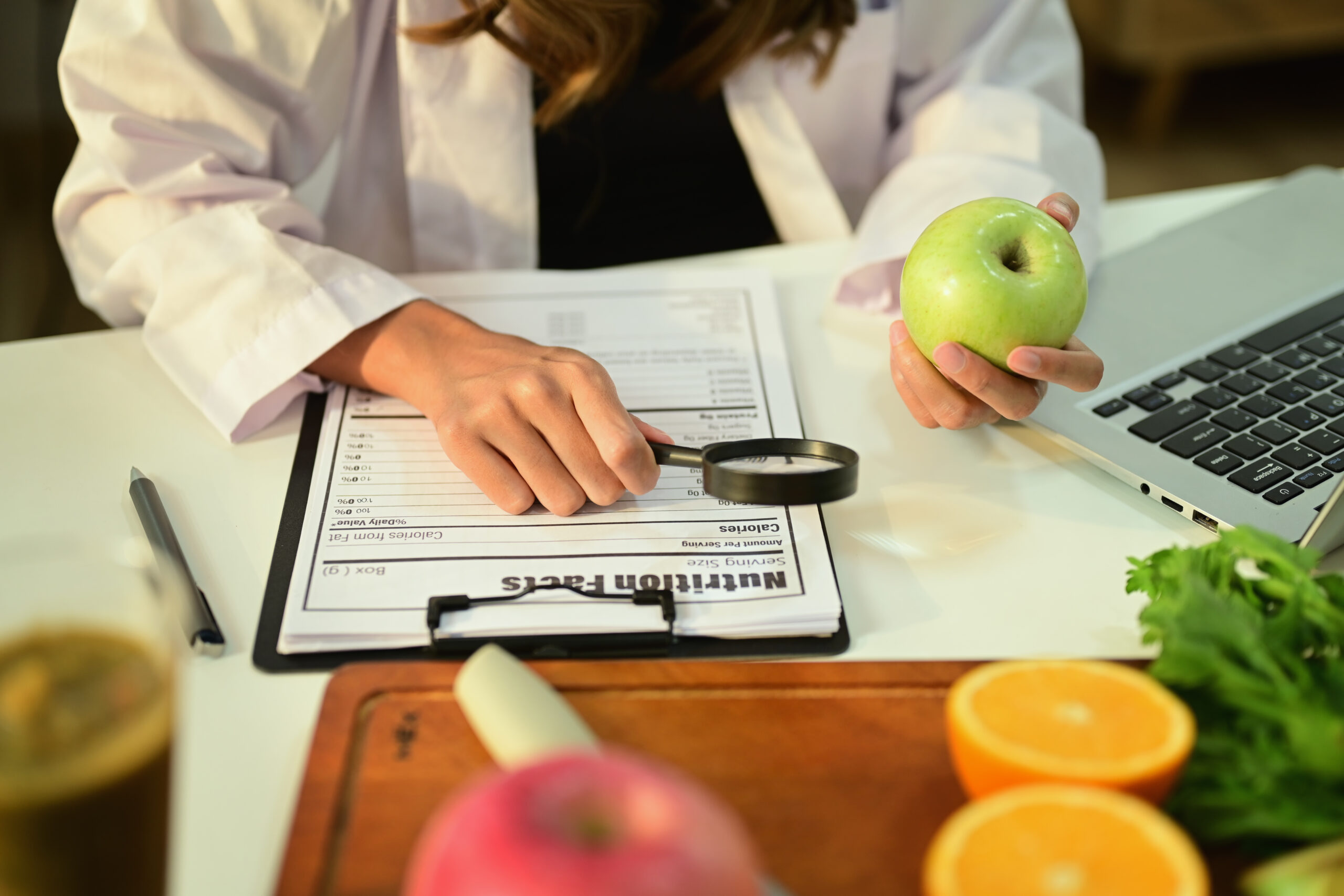 Cropped image of nutritionist holding an apple and prescribing r
